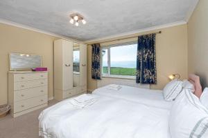 a bedroom with two white beds and a window at Plas Diwedd in Valley