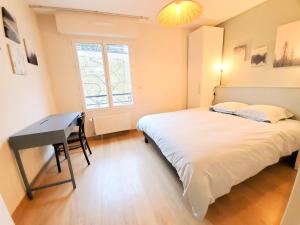 Un dormitorio con una cama y un escritorio y una ventana. en Standing appartement avec vue sur la Mayenne, en Laval