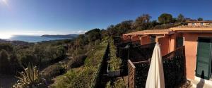 un bâtiment avec un parasol sur le côté d'une colline dans l'établissement Ca' La Stella Sea-view Apartments, à Porto Azzurro