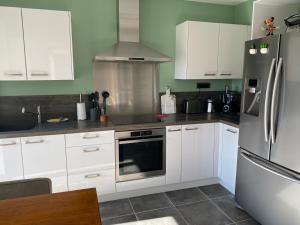 a kitchen with white cabinets and a stainless steel refrigerator at Villa Ghjuvan - Sea, Mountain & Spa in Peri