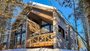 une maison dans les bois dans la neige dans l'établissement Le Bleu Bourgeois de Portneuf - Natural Elegance - Hot tub, sauna and pool, à Pont-Rouge