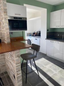 a kitchen with white cabinets and a table and a chair at Villa Ghjuvan - Sea, Mountain & Spa in Peri