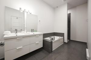 a white bathroom with two sinks and a tub at NEW Spacious Industrial Loft in Le Plateau by Den Stays in Montreal