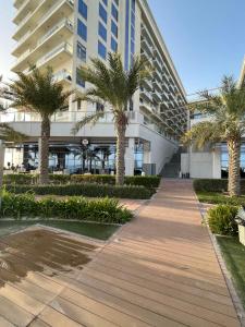 a walkway in front of a building with palm trees at Breathtaking Studio Apartment in Marjan Island in Ras al Khaimah