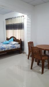 1 dormitorio con 1 cama, mesa y sillas en Anura Home Stay, en Kalutara