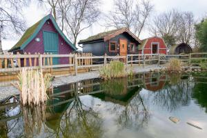 un groupe de maisons assises à côté d'un étang dans l'établissement Seaways glamping, Cedar, à Great Driffield