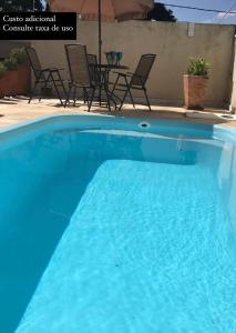 uma piscina azul com cadeiras e um guarda-sol em Casa Aconchego em Itu