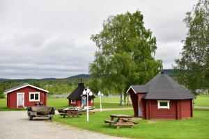 um grupo de pequenos edifícios com uma mesa de piquenique e bancos em Lappland Pro Natur em Åsele