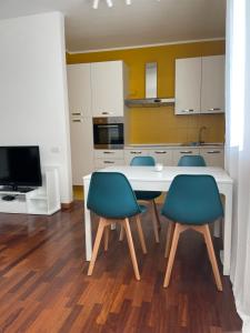 kuchnia z białym stołem i niebieskimi krzesłami w obiekcie BICOCCA APARTMENT w Mediolanie