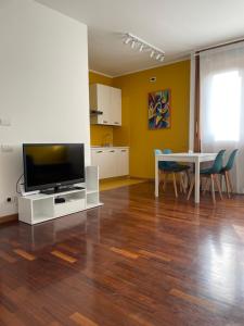 Il comprend un salon doté d'une télévision et d'une table avec des chaises. dans l'établissement BICOCCA APARTMENT, à Milan