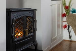 a black wood stove in a living room with two chairs at Conwy View Cottage in Conwy