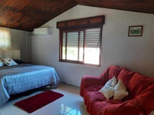 1 dormitorio con cama, sofá y ventana en Serena, en Barra del Chuy