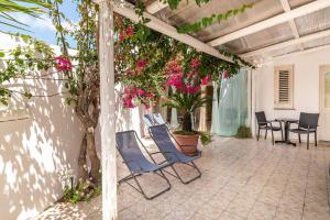 un patio con sillas azules y una mesa con flores rosas en Stromboli Central Family Apartment - 3 Double Rooms en Stromboli