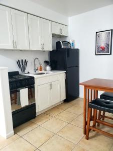a kitchen with white cabinets and a black refrigerator at Singer Island Inn in West Palm Beach