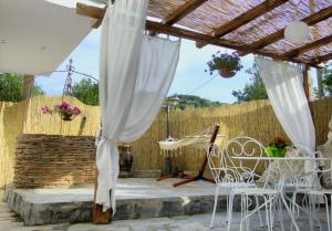 un patio con sillas blancas y pérgola en Casa Vacanze Borgo Borghese, en SantʼAlessio Siculo
