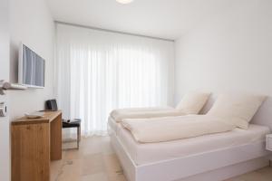 Camera bianca con letto e TV di Penthaus 15 Strandvilla Therese a Norderney