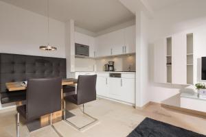 una cucina con armadi bianchi e tavolo e sedie in legno di Penthaus 15 Strandvilla Therese a Norderney Altre 5 foto
