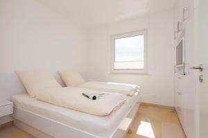 un divano bianco in una camera bianca con finestra di Penthaus 15 Strandvilla Therese a Norderney
