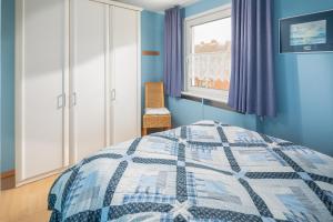 a blue bedroom with a bed and a window at Rubintje Nord in Norderney