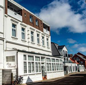ein weißes Gebäude mit Fenstern auf einer Straße in der Unterkunft Haus Westwind Hallwegh 04 in Norderney