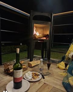 una bottiglia di vino seduta su un tavolo con pizza e forno di Acogedor y moderno Glamping en container, 10 min del centro a Chiquinquirá