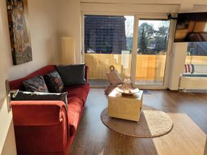 a living room with a red couch and a table at Ferienwohnung Casa Di Lago 2 in Heinsberg