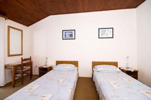 two beds in a room with a table and two chairs at Apartment Srđ in Dubrovnik