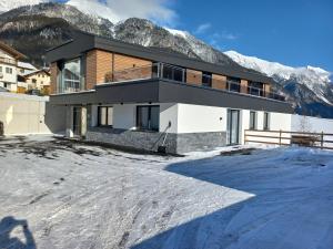 a house in the snow with mountains in the background at Apart Sopherl in Pettneu am Arlberg
