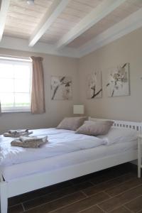 a white bed in a white bedroom with a window at Ferienhäuser Salzhaff-Romantik in Teßmannsdorf