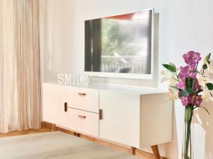 a white dresser with a mirror and a vase with flowers at Apartamentos Zaragoza in Salou