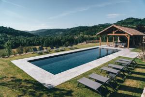 a swimming pool with chairs and a gazebo at La ferme d'Edouard - Les Fermes Ardéchoises in Labatie-dʼAndaure