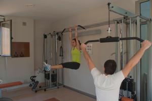 un hombre y una mujer haciendo un ejercicio colgando en un gimnasio en El Salugral Termal Resort, en Hervás