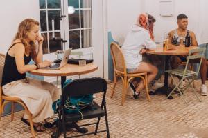 eine Gruppe von Personen, die an einem Tisch mit einem Laptop sitzen in der Unterkunft Selina Peniche in Peniche