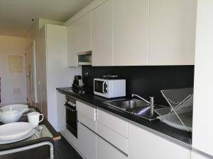 eine weiße Küche mit einer Spüle und einer Mikrowelle in der Unterkunft Welcome Here - Tamisa - Parque das Nações in Lissabon