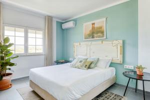 a bedroom with a white bed and white walls at Selina Peniche in Peniche