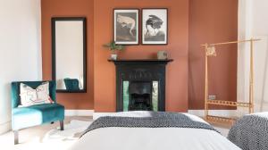 a bedroom with orange walls and a fireplace at Tŷ Hapus Newport - Luxury 4 Bedroom Home in Newport