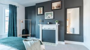 a bedroom with a fireplace and a mirror at Tŷ Hapus Newport - Luxury 4 Bedroom Home in Newport