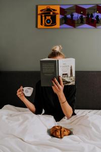 a woman laying in bed reading a book at Hotel Brasserie Brakzand in Schiermonnikoog