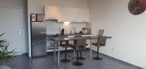 a kitchen with a table and a refrigerator at Appartement-chic parking privé in Tourcoing