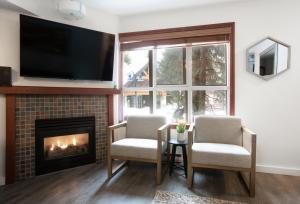 uma sala de estar com duas cadeiras e uma lareira em Attractive Townhouse in Whistler Village with Hot Tub em Whistler
