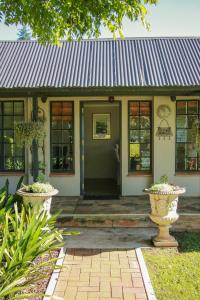 ein Haus mit einem Metalldach und einer Veranda in der Unterkunft Idavold Gate House in Howick