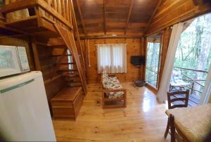 a living room with a staircase in a log cabin at POUSADA CABANA TIO ZEZO in Esteves Júnior