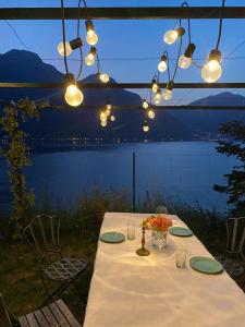a table with a white table cloth and lights at GLI ORTI DELLA CIVERA " Cottagecore" Amazing View in Nesso