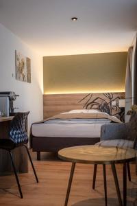 Hotel & Restaurant Bären في Niederbipp: غرفة نوم بسرير وطاولة وكراسي