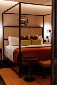 a bedroom with a four poster bed with a stool at Casa Hoyos - Hotel Boutique in San Miguel de Allende