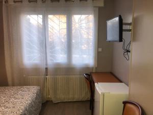 a bedroom with a window and a desk with a television at Hotel les Troenes in Montpellier