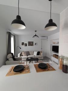 a white living room with two black pendant lights at ARTE Playa la Caleta Grupo AC Gestion in Cádiz