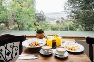 un tavolo con due piatti di prodotti per la colazione e succo d'arancia di Hotel Monteluna a Bogotá
