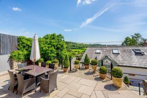 un patio con mesa, sillas y sombrilla en Broadrock Accommodation - Clock Cottage, en Chepstow