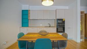a kitchen with a wooden table and blue chairs at HVA Premium Apartments in Braşov